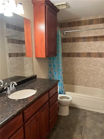 a bathroom with a granite countertop sink a toilet a mirror and bathtub