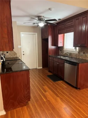 a kitchen with stainless steel appliances granite countertop a sink dishwasher stove and refrigerator with wooden floor