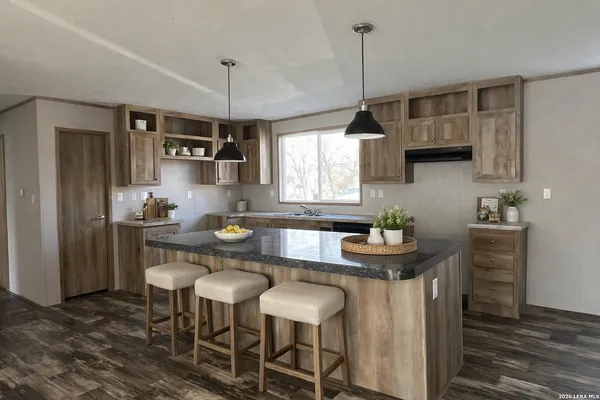 a kitchen with granite countertop a table chairs stove and microwave