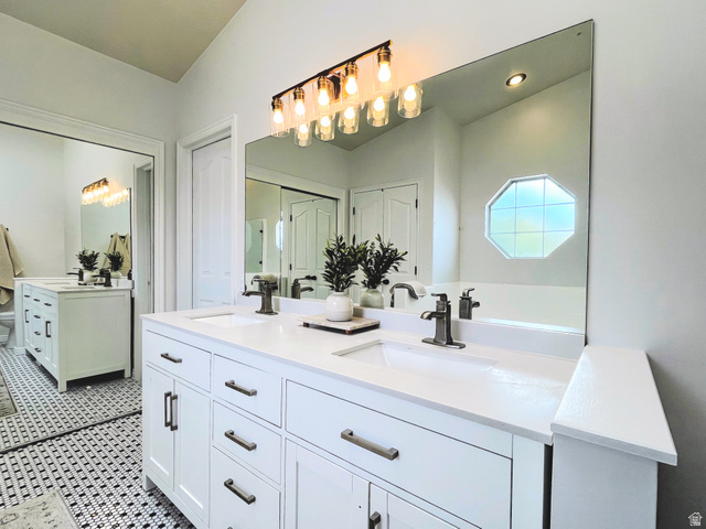 12169 Hidden Valley Road, Unit 44 Sandy, UT 84092 - Photo 21 of 49 Dual white vanities with integrated sinks, brushed nickel fixtures, a large frameless mirror, and a black and white mosaic tile floor