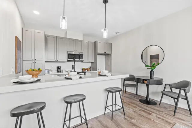 a kitchen with stainless steel appliances granite countertop a sink a stove a refrigerator cabinets and chairs