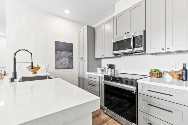 a kitchen with stainless steel appliances granite countertop a stove a sink and a white cabinets