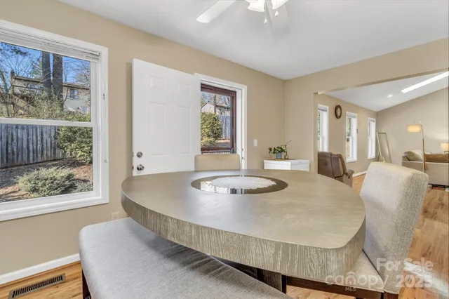a dining room with wooden floor and large windows