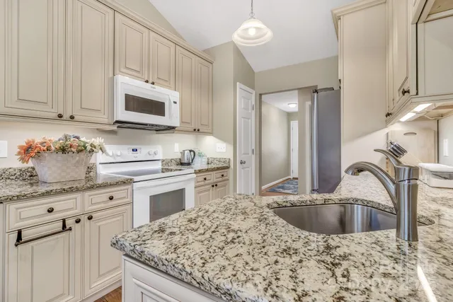 a kitchen with granite countertop a sink a stove and cabinets