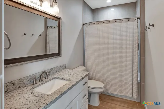 a bathroom with a granite countertop sink toilet and shower