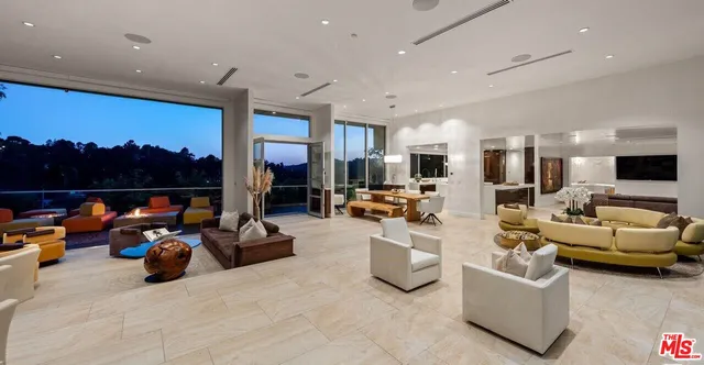 a living room with furniture kitchen view and a large window