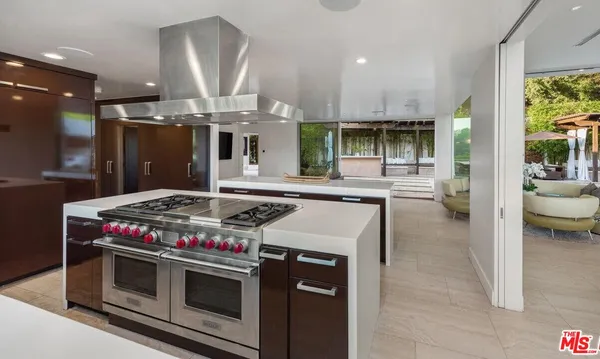 a kitchen with a stove and a view of living room