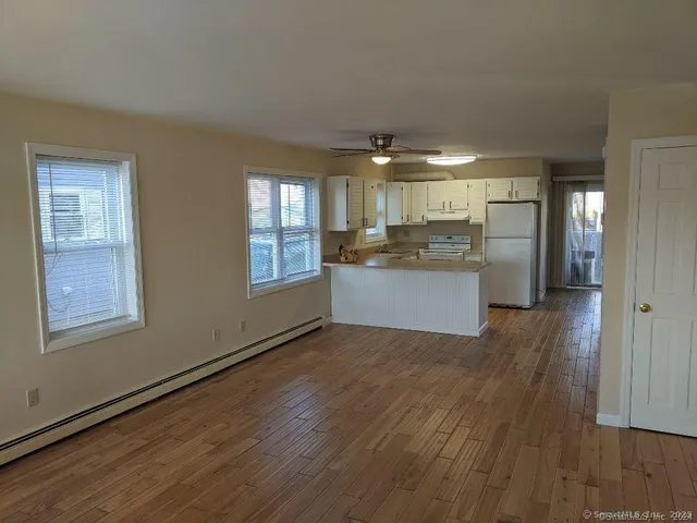 a kitchen with stainless steel appliances granite countertop a refrigerator a sink dishwasher a stove and white countertops with wooden floor