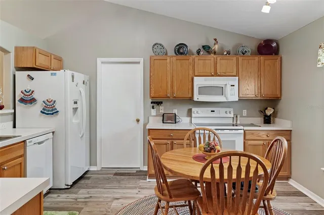 a kitchen with stainless steel appliances granite countertop a refrigerator a stove a sink and a dining table with wooden floor