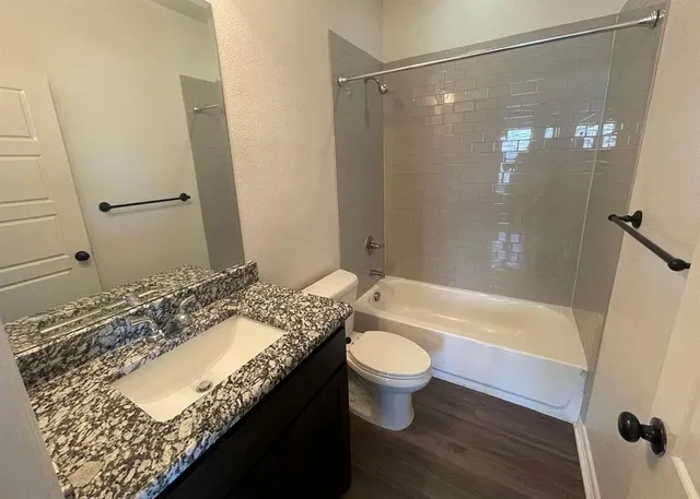 a bathroom with a granite countertop sink toilet mirror and bathtub
