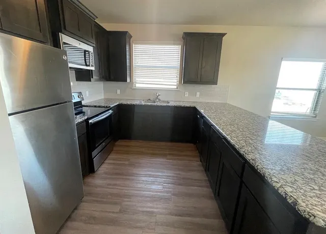 a kitchen with granite countertop a refrigerator and a sink