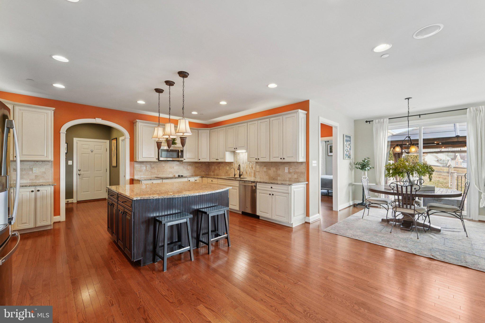 420 Irish Rebel Road Westminster, MD 21157 - Photo 17 of 71 a living room with stainless steel appliances kitchen island granite countertop a kitchen island a stove a refrigerator a dining table and chairs with wooden floor
