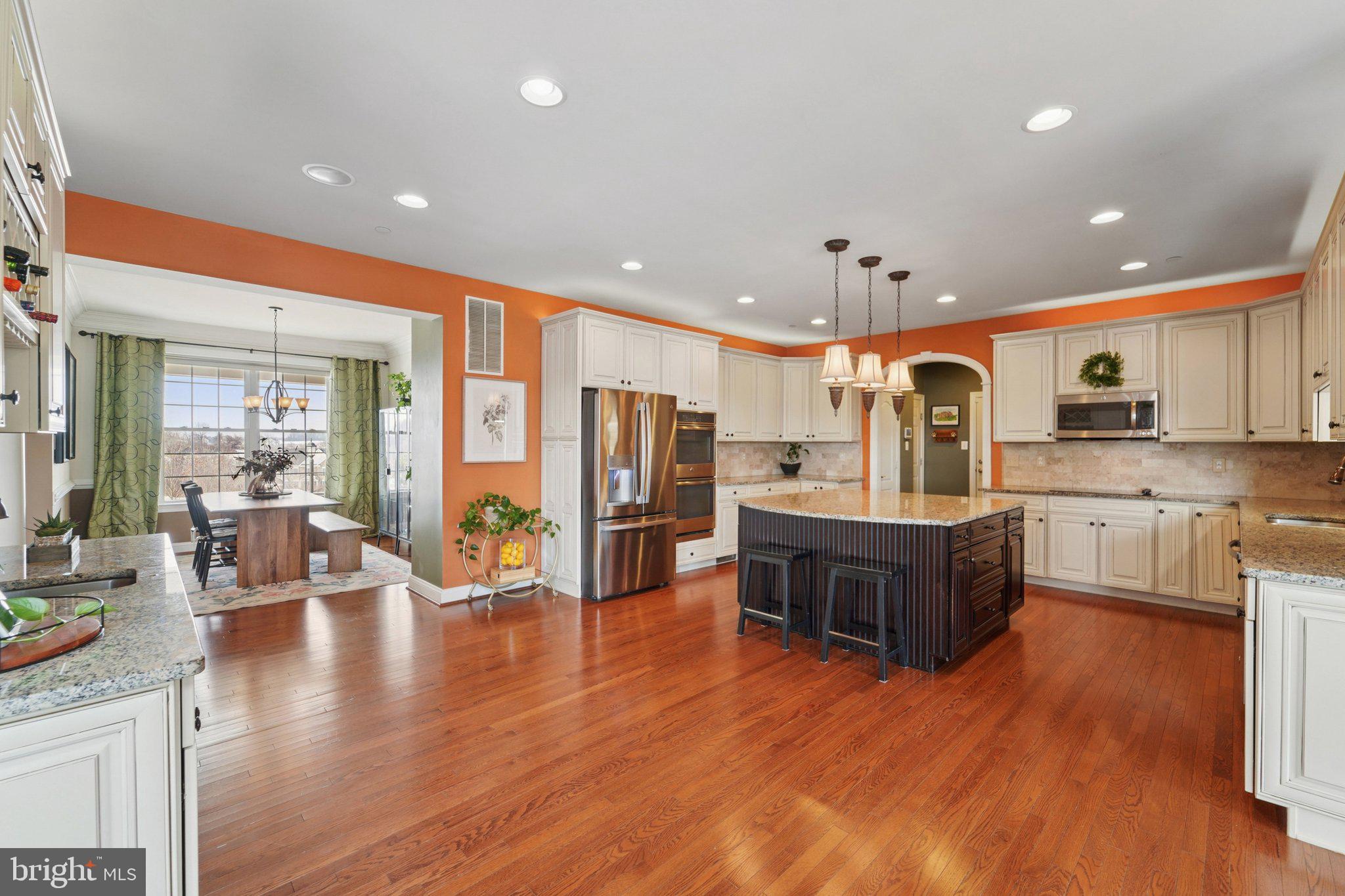 420 Irish Rebel Road Westminster, MD 21157 - Photo 21 of 71 a open kitchen with stainless steel appliances granite countertop a refrigerator a sink dishwasher a dining table and chairs with wooden floor