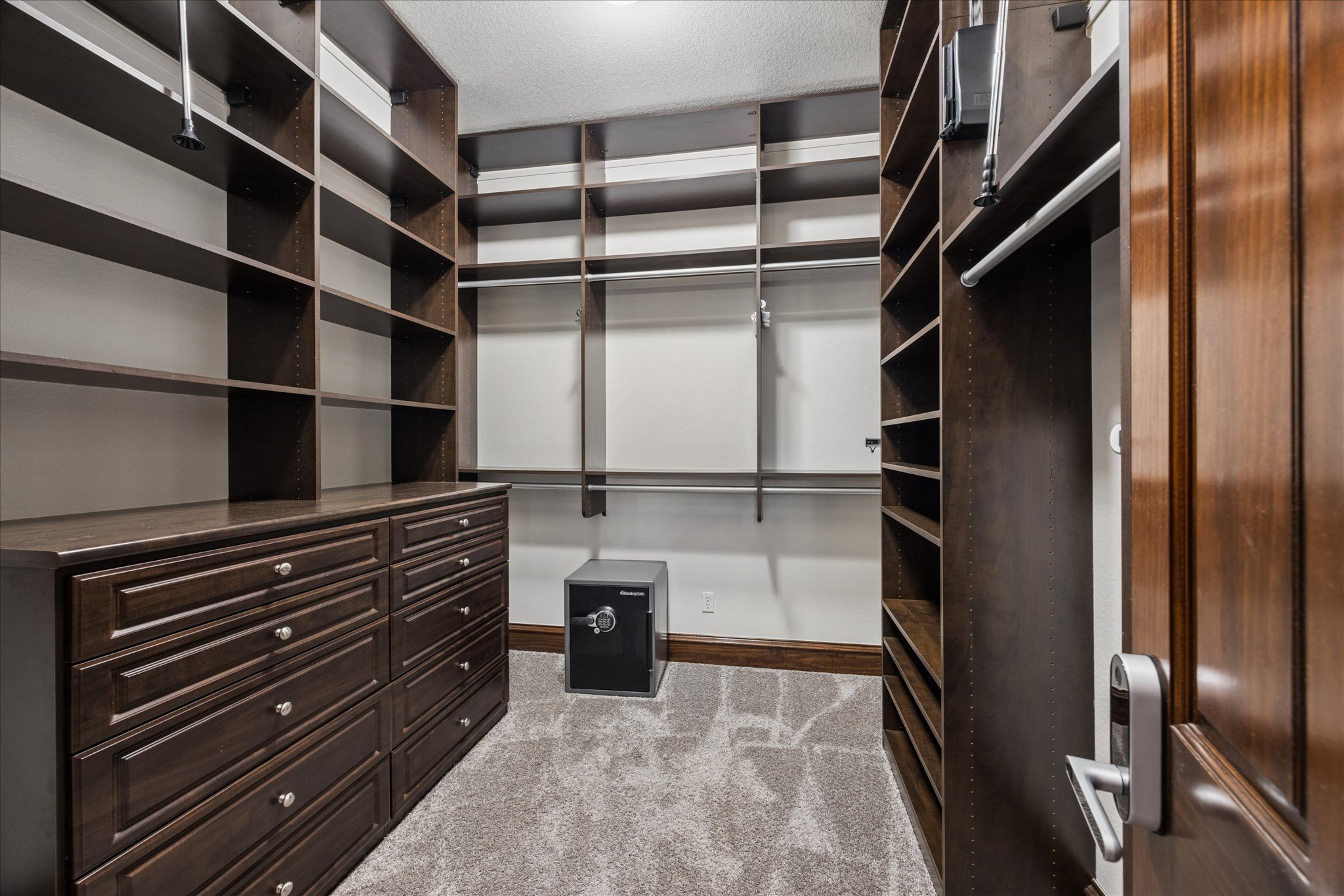 11805 Ranchview Court Austin, TX 78732 - Photo 14 of 36 Expansive custom closet featuring dark wood-finish cabinetry, built-in shelving, hanging rods, and a central dresser with multiple drawers