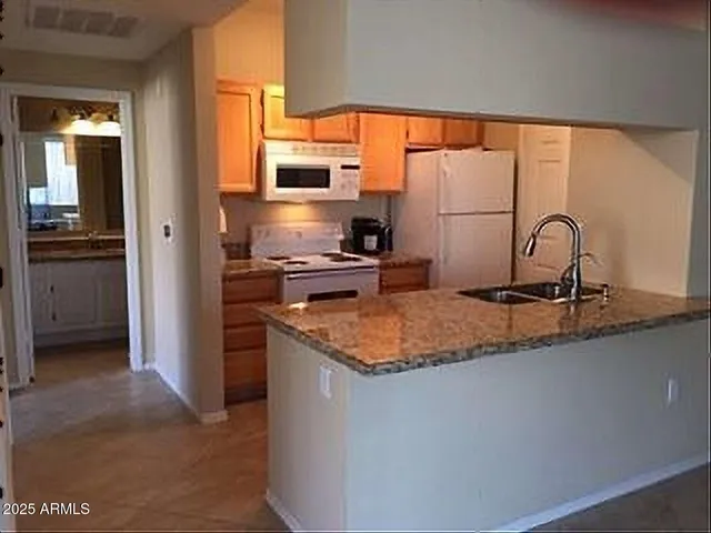 a kitchen with stainless steel appliances granite countertop a sink a stove and a refrigerator