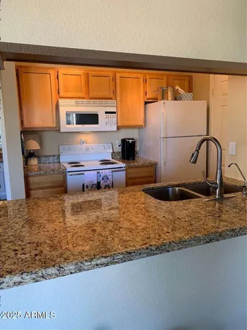 a bathroom with a granite countertop sink and a large mirror next to a large window