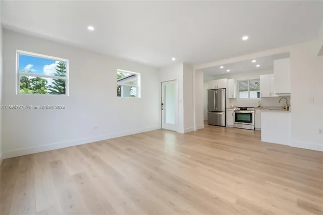 an empty room with stainless steel appliances kitchen island granite countertop a refrigerator and a stove top oven