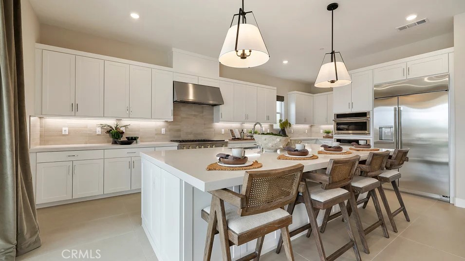 a kitchen with stainless steel appliances a dining table chairs and sink