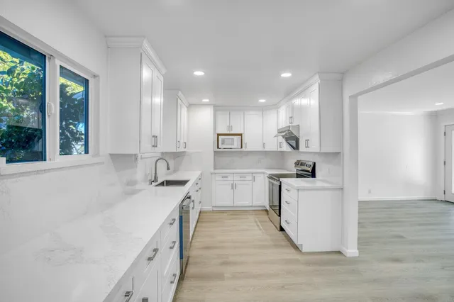 a view of an empty room with wooden floor and window