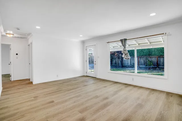 a view of an empty room with wooden floor and a window