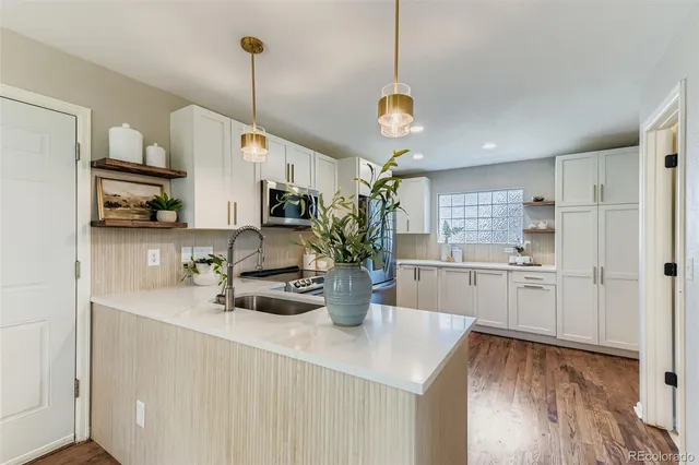 a kitchen with a refrigerator a sink dishwasher a oven with white cabinets and wooden floor