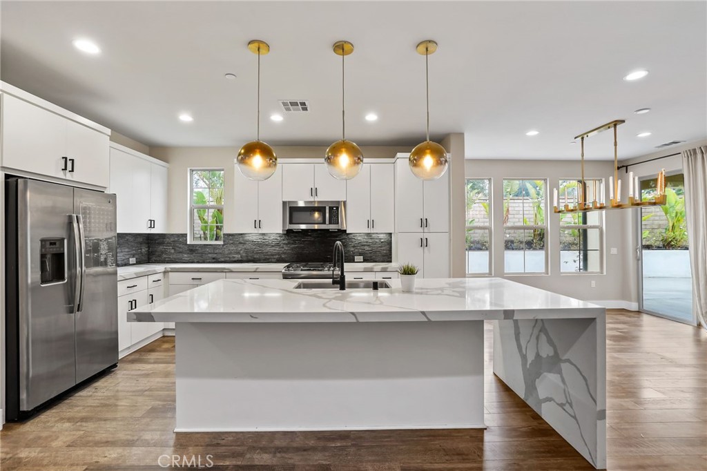 a large kitchen with kitchen island a large counter space a sink appliances and cabinets