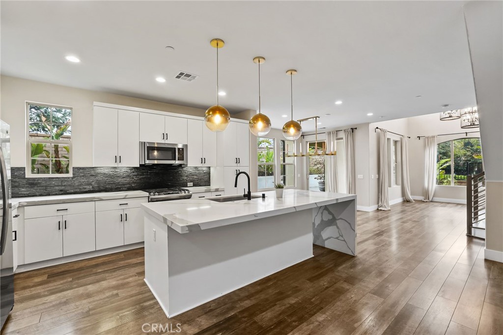 51 Prominence Lake Forest, CA 92630 - Photo 18 of 60 a kitchen with stainless steel appliances kitchen island granite countertop a stove a sink and a wooden floors