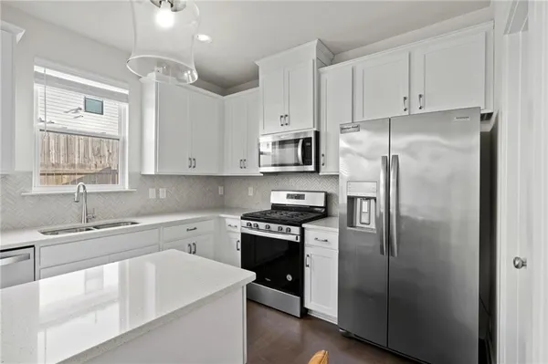 a kitchen with white cabinets and stainless steel appliances