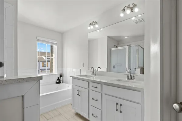 a bathroom with a tub a sink double vanity and a mirror