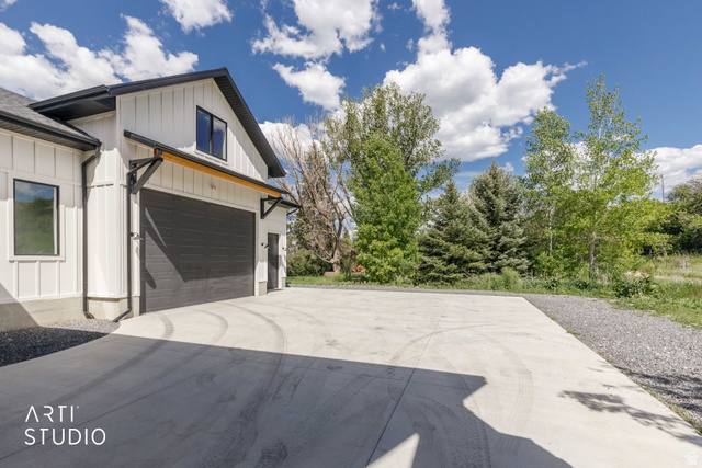 1188 South Old Trappers Loop Road Huntsville, UT 84317 - Photo 14 of 92 Modern farmhouse exterior featuring vertical white siding, a dark gray garage door, black-framed windows, and a concrete driveway