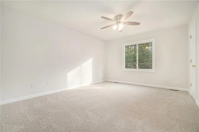 an empty room with a chandelier fan and windows