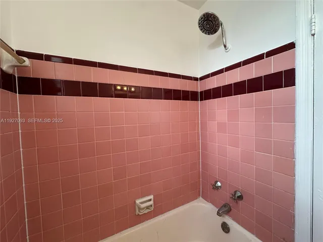 a bathroom with a shower and a tiled wall