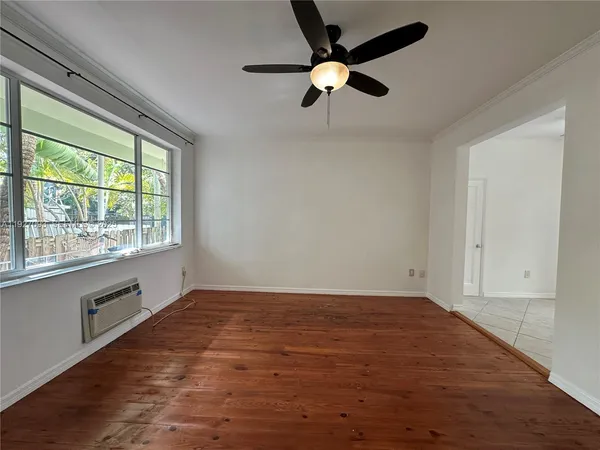 an empty room with a window and a fan