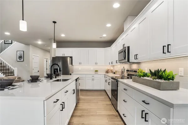 a kitchen with kitchen island granite countertop a sink a counter space appliances and cabinets