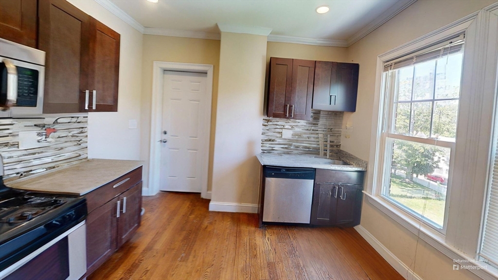 2973 Washington Street, Unit 3 Boston, MA 02119 - Photo 1 of 6 a kitchen with kitchen island wooden floors appliances and cabinets