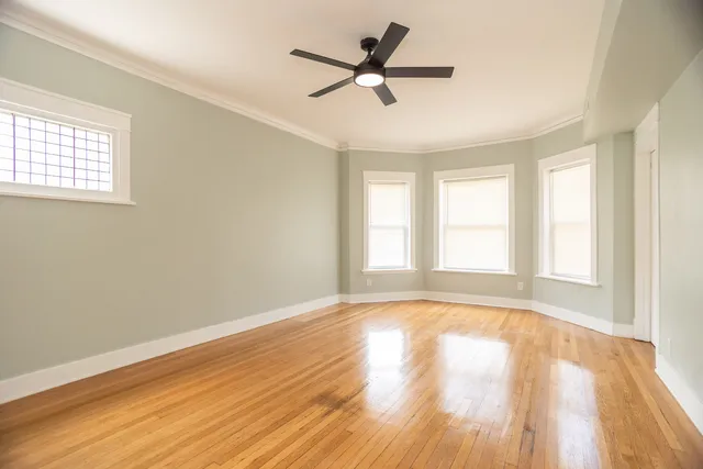 a view of empty room with wooden floor and fan