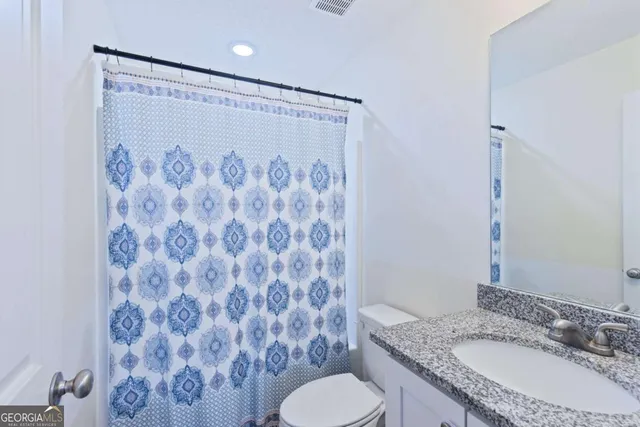 a bathroom with a granite countertop sink toilet and a mirror