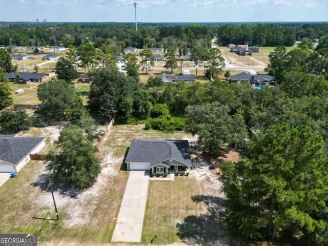 an aerial view of a house with a yard and large trees