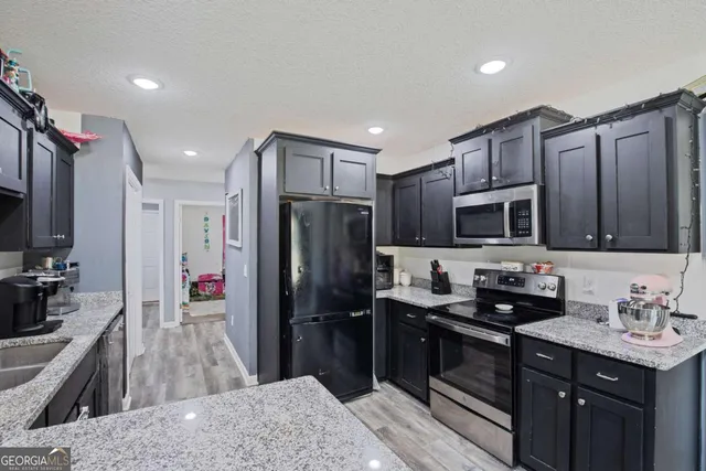 a kitchen with stainless steel appliances granite countertop a refrigerator a sink a stove a microwave and wooden cabinets