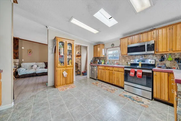 a living room with stainless steel appliances furniture and a open kitchen view