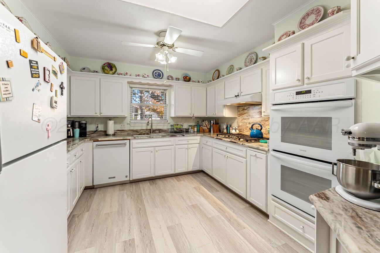 201 Carson Avenue Dumas, TX 79029 - Photo 12 of 55 a kitchen with granite countertop white cabinets and white appliances