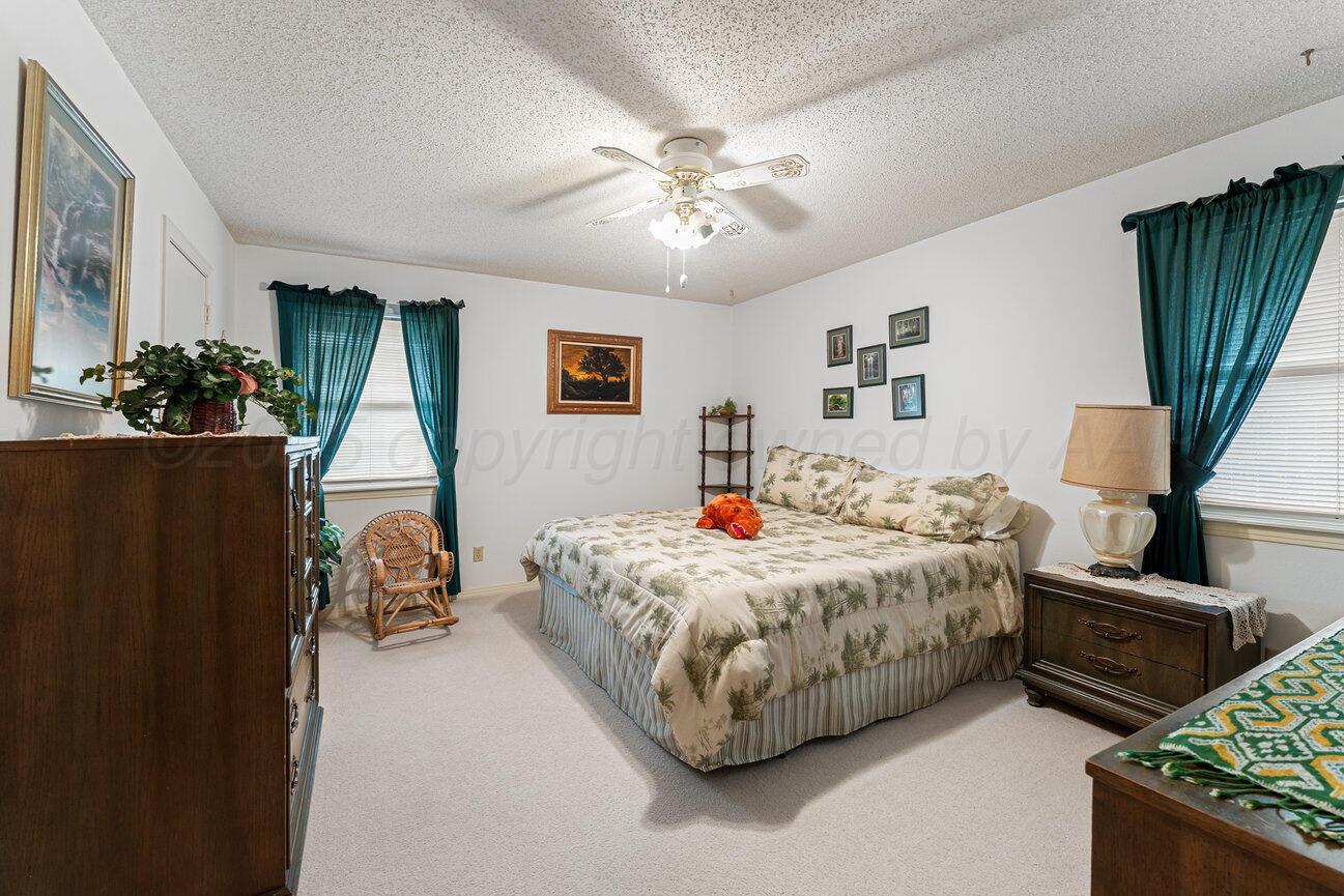 201 Carson Avenue Dumas, TX 79029 - Photo 27 of 55 a spacious bedroom with a bed and a chandelier
