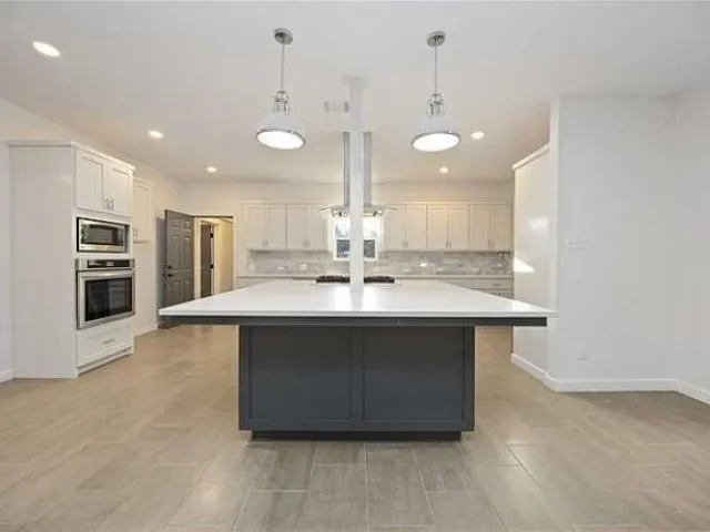 a large kitchen with kitchen island a sink stainless steel appliances and a fireplace