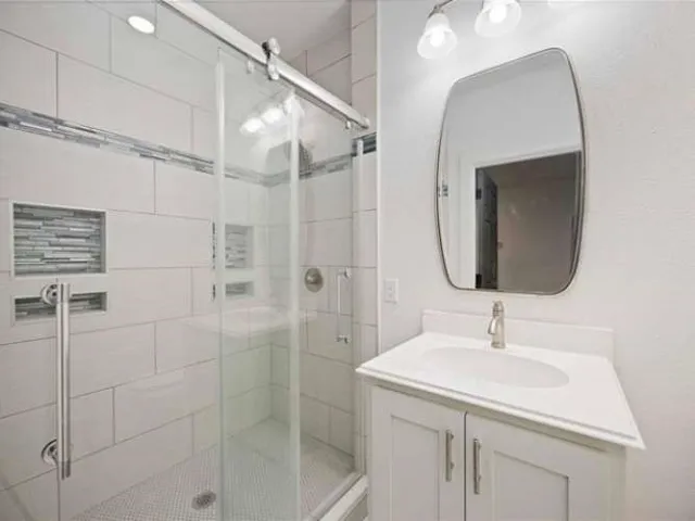 a bathroom with a sink shower and a mirror