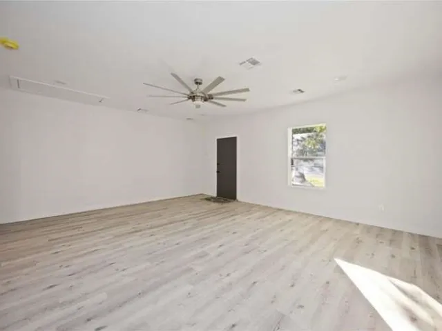 an empty room with windows and fan