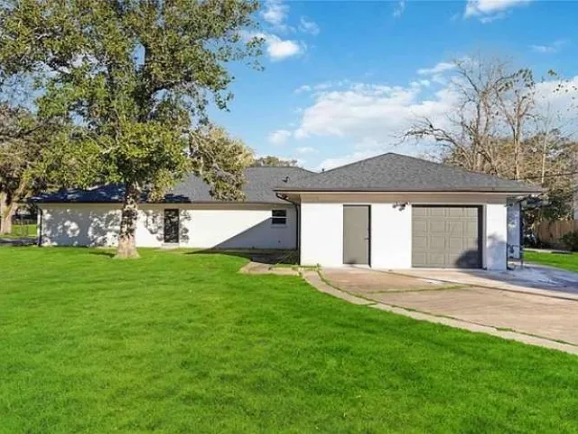 a view of a house with a yard and a large tree