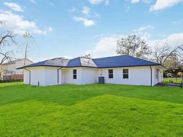 a view of a house with a big yard potted plants and a tree