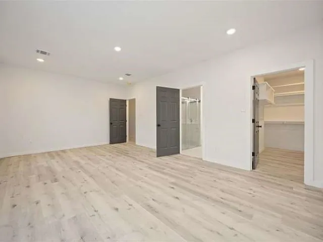 a view of an empty room with wooden floor and closet