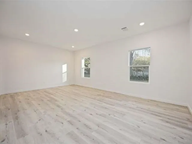 a view of empty room with wooden floor and fan
