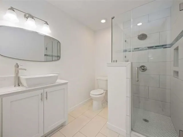 a bathroom with a toilet a sink a mirror and shower